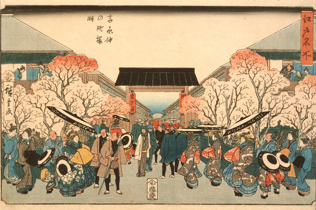 A colour woodblock print of a wide street lined with cherry trees in bloom, with a procession of women in elaborate robes and crowds in the foreground